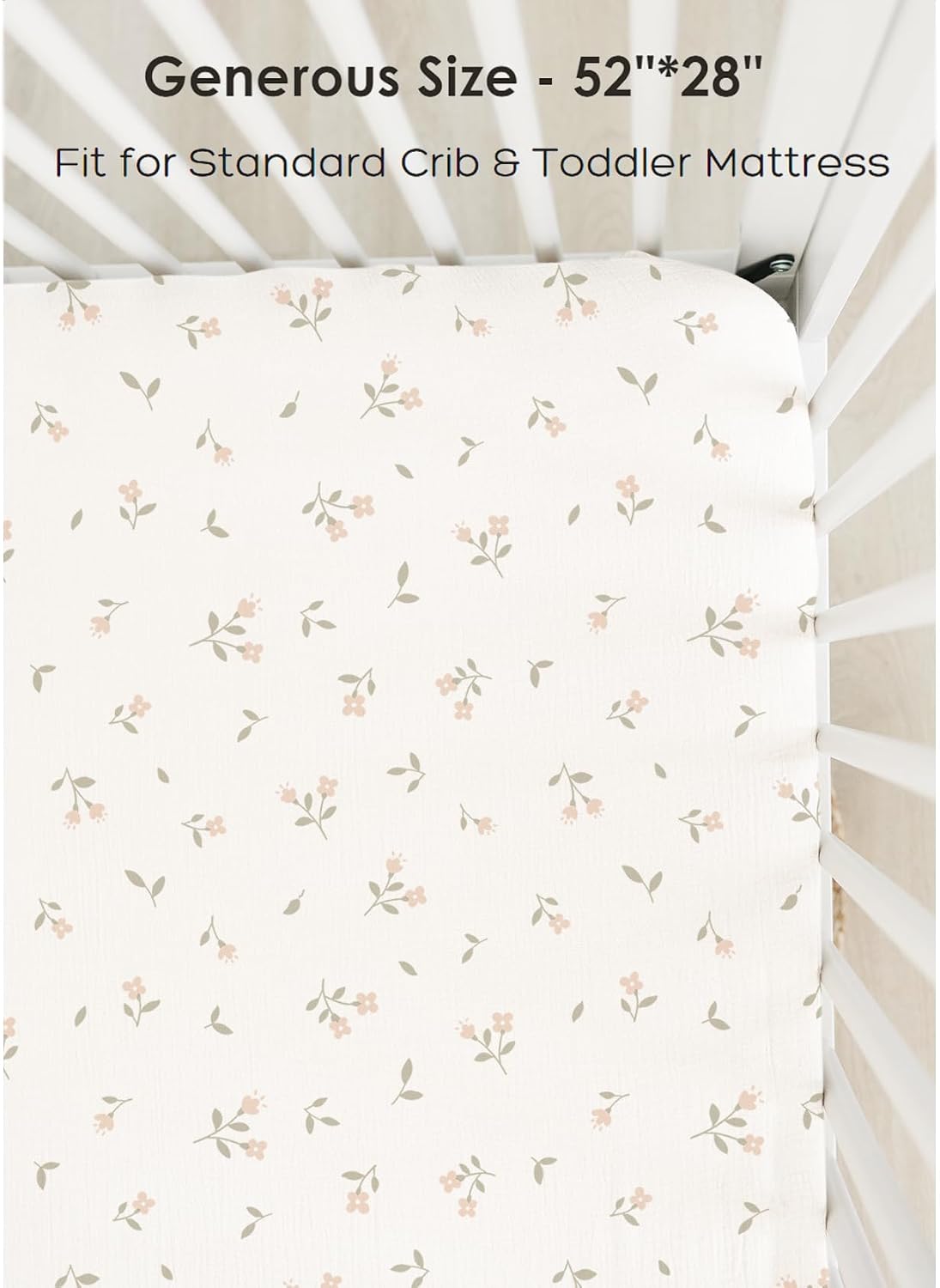 Fitted crib sheet with an all-over small floral print in soft pink blooms and sage green leaves on a cream background, shown fitted on a crib mattress. Text reads 'Generous Size - 52"*28"' and 'Fit for Standard Crib & Toddler Mattress'.