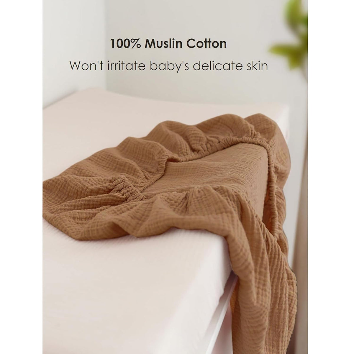 Caramel-brown muslin cotton changing pad cover fitted over a white changing pad, shown with its textured crinkled fabric. Text reads '100% Muslin Cotton - Won't irritate baby's delicate skin.'