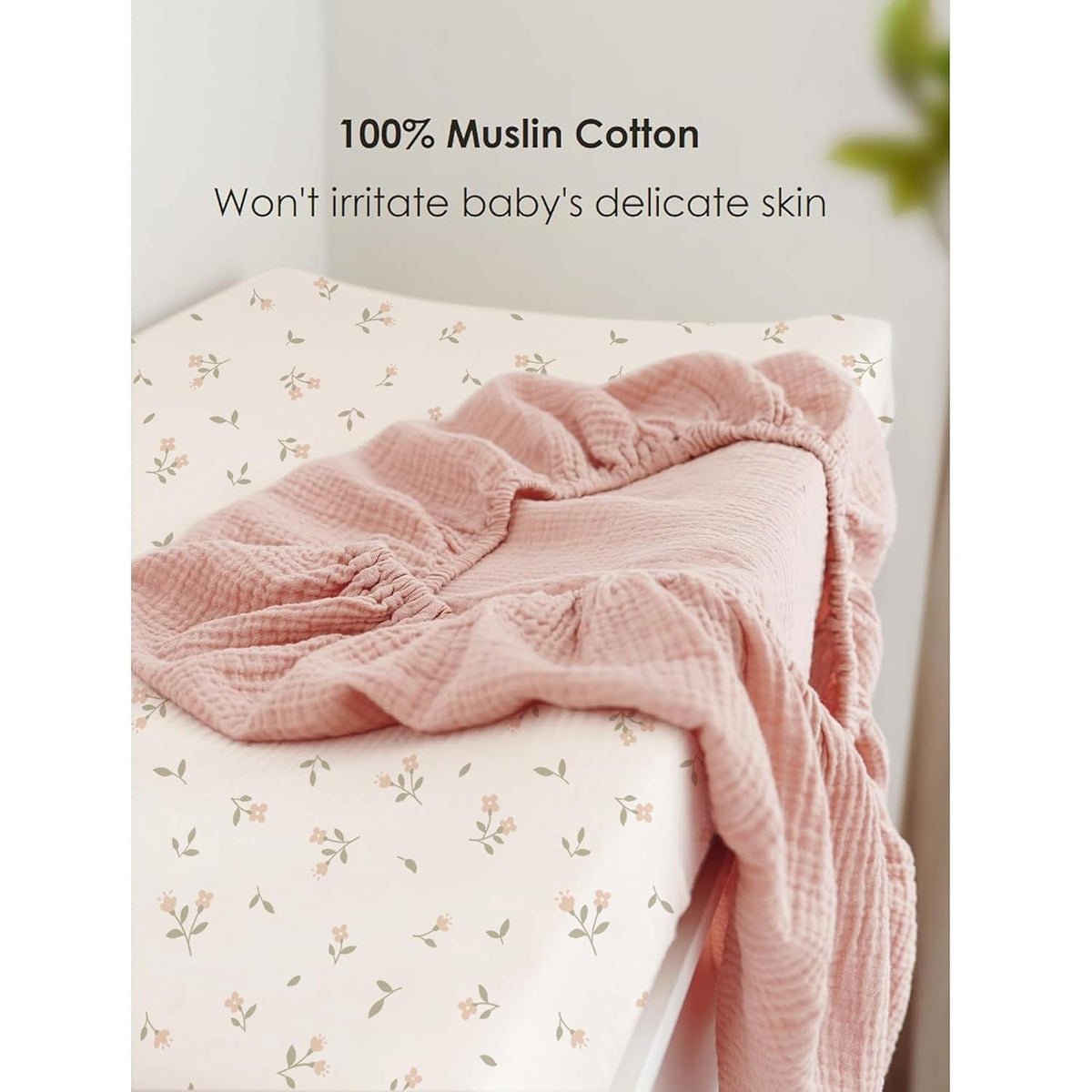 Two muslin cotton changing pad covers: one fitted on a changing pad with a small floral print on cream background, and one dusty pink textured muslin cover draped on top. Text reads '100% Muslin Cotton - Won't irritate baby's delicate skin.'