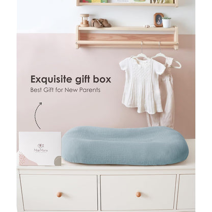 Dusty blue textured muslin lounger cover on a white dresser beside a white gift box labeled MairMore. Text reads 'Exquisite gift box - Best Gift for New Parents.' Baby clothes hang in background.