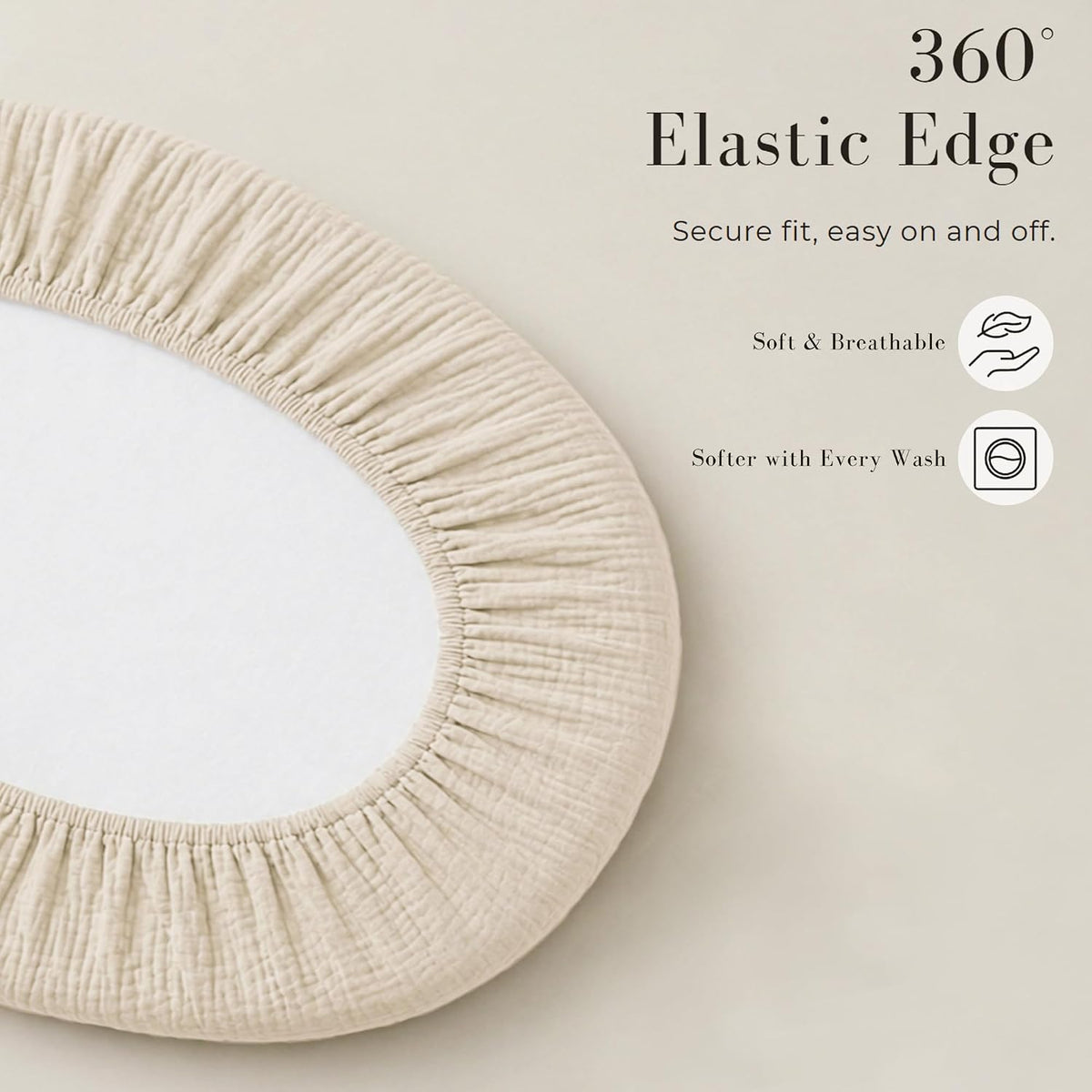 Oval fitted bassinet sheet in light beige muslin fabric shown from above, with gathered elastic edging around the perimeter. Text reads '360 Degree Elastic Edge - Secure fit, easy on and off,' with icons for Soft & Breathable and Softer with Every Wash.