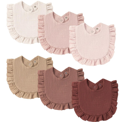 Six ruffled baby bibs in a muslin cotton texture arranged in two rows. Colors include cream, dusty rose, light pink, tan, mauve, and dark burgundy. Each bib has a snap closure at the neck and a ruffled hem.