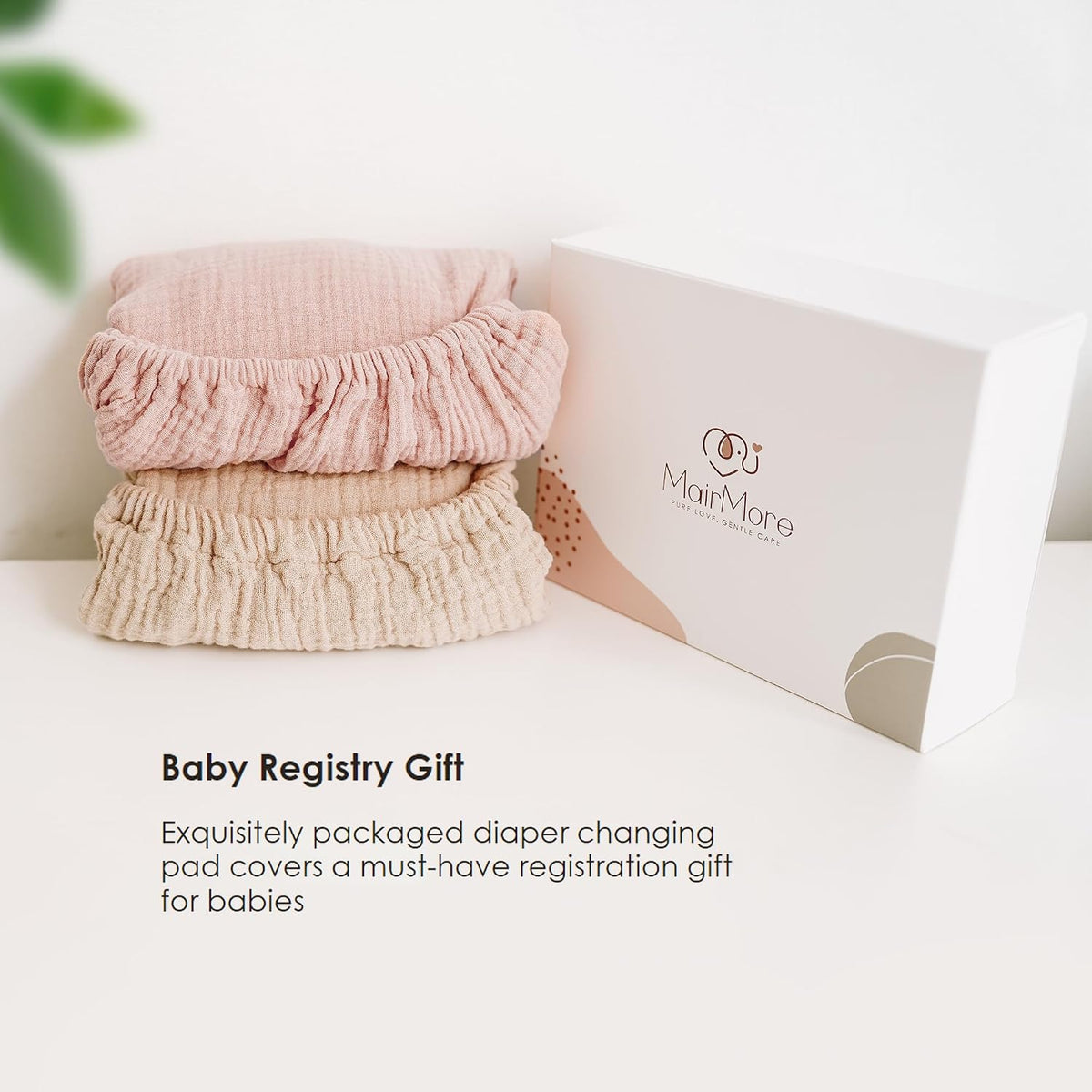 Two folded muslin changing pad covers stacked beside a white MairMore gift box. Top cover is dusty pink, bottom is ivory/cream. Both show textured gathered edges. Text reads 'Baby Registry Gift' below.