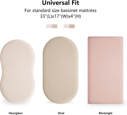 Infographic showing bassinet fitted sheets in three mattress shapes: Hourglass, Oval, and Rectangle. The Hourglass and Oval sheets are ivory/cream; the Rectangle sheet is pink. Text reads 'Universal Fit for standard size bassinet mattress 33"(L)x17"(W)x4"(H)'.