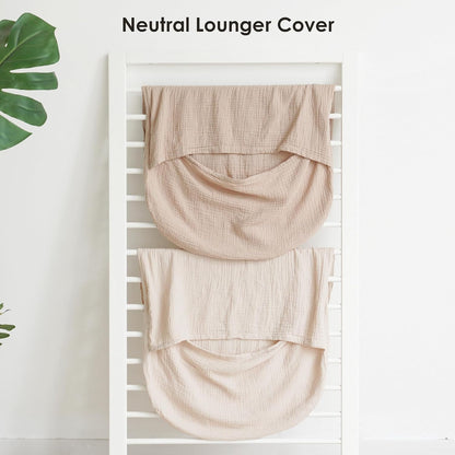 Two soft beige muslin baby lounger covers draped over a white slatted rack, showing their rounded bottom shape and textured cotton weave. Text reads 'Neutral Lounger Cover' at top.