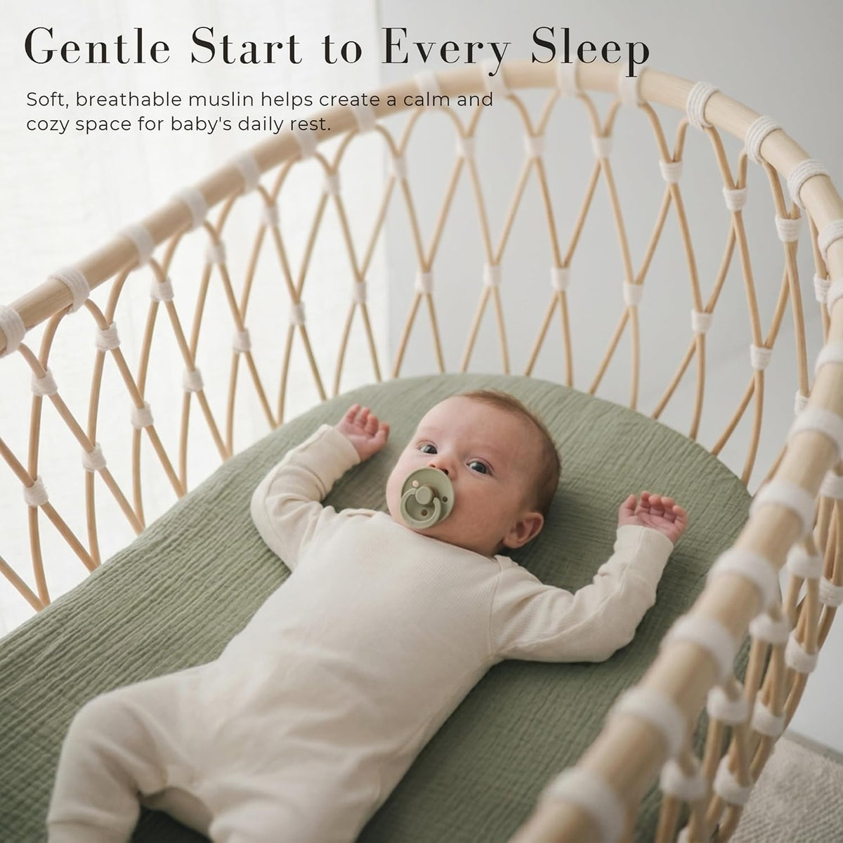 Baby lying on a sage green muslin fitted sheet inside a woven rattan bassinet. The textured cotton sheet has a subtle grid pattern. Text reads 'Gentle Start to Every Sleep' with a breathable muslin callout.