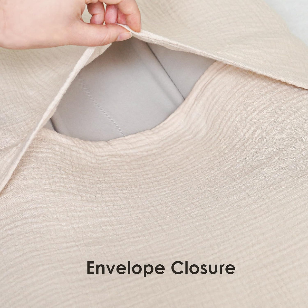 Close-up of a textured cream muslin fabric cover being pulled open to reveal a gray interior, demonstrating the envelope closure. Bold text at bottom reads 'Envelope Closure'.