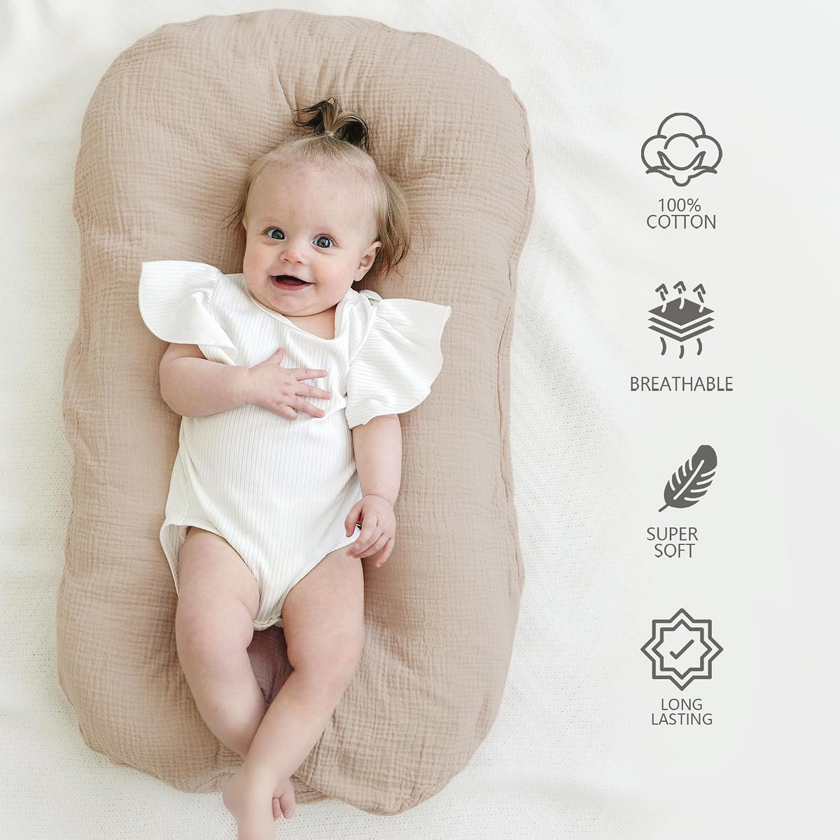 Baby lying on a tan/clay-colored muslin cotton lounger cover, viewed from above. The cover has a soft, textured fabric surface. Icons on the right list: 100% Cotton, Breathable, Super Soft, and Long Lasting.