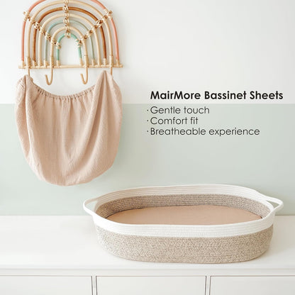 MairMore Bassinet Sheets promotional image showing a soft beige muslin fitted sheet hanging on a decorative rainbow wall hook, alongside an oval rope bassinet on a white surface. Text lists: Gentle touch, Comfort fit, Breathable experience.
