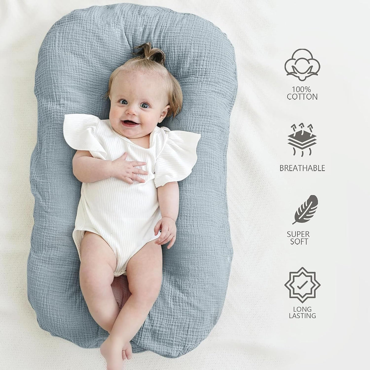 Baby lying on a gray-blue muslin cotton lounger cover with textured fabric. Four icons on the right highlight product features: 100% Cotton, Breathable, Super Soft, and Long Lasting.