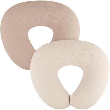 Two U-shaped nursing pillow covers in a textured woven fabric. The back cover is medium taupe and the front cover is cream/off-white. Both show a fine muslin-like weave texture and a U-shaped opening at the bottom.