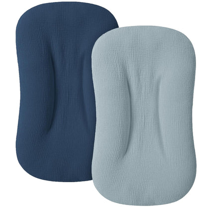 Two muslin fabric lounger covers shown side by side on a white background. The left cover is dark navy blue and the right is light steel blue, both with a rounded rectangular shape and visible textured weave.