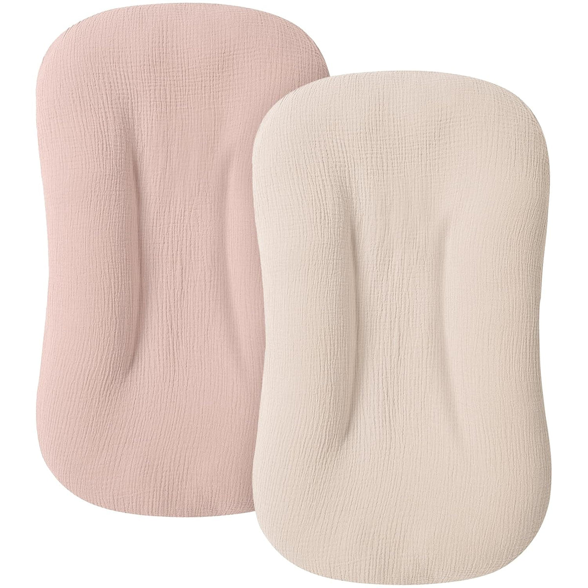 Two baby lounger covers in muslin fabric shown side by side: a dusty pink cover on the left and a cream/ivory cover on the right. Both have a rounded rectangular shape with a textured woven surface.