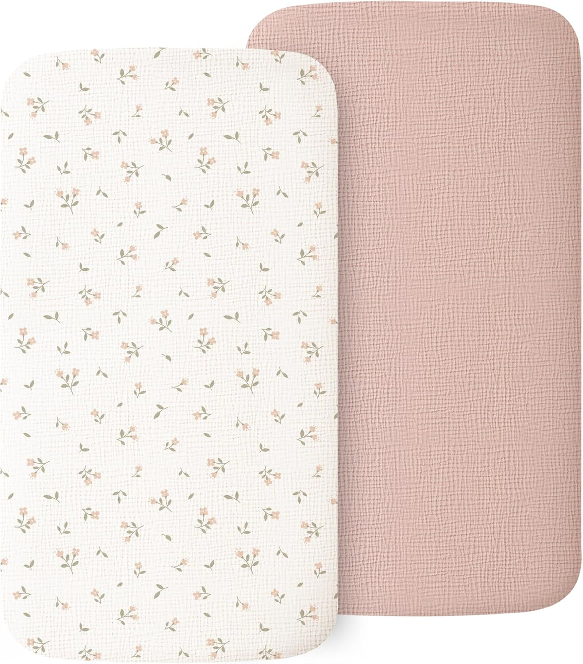 Two muslin fitted bassinet sheets with rounded corners. The front sheet is white with a scattered small pink floral and green leaf pattern. Behind it is a solid dusty pink sheet with a subtle textured weave. Both have a soft, woven fabric appearance.